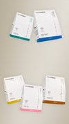 Cinque box bianche Maraes Travel Kit con fasce colorate su sfondo beige