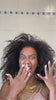 Woman with voluminous natural curly hair making an expressive surprised gesture in a bathroom setting, showcasing texture, body, and movement of dark curly hair.