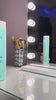 Aqua-blue Purify Filler shampoo bottle positioned on a vanity table beside a makeup brush holder and illuminated mirror lights, with the product reflected in the mirror and glossy surface below.